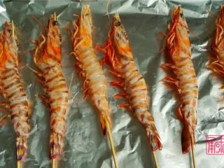 承味普罗旺斯迷迭香烤虾,先用对半切的蒜涂在烤纸上，虾用竹签串好后放在烤盘上