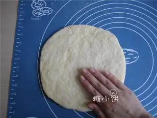 烟熏风味BBQ烤鸡肉披萨,在面板上撒多一点玉米面防粘，放上第一步松弛好的面团，用双手从圆心往外抹面团，抻成圆饼状。如图其中一只手的位置就是像这样，由圆心处向外抹。两只手一起，边抹边把面饼转圈这样各个方向都比较均匀，期间可以补些玉米面防粘。