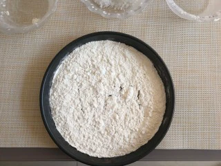 老北京小吃艾窝窝,把面粉导入烤盘中,平摊。