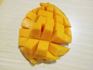 #冬喝暖饮夏吃冰#健康低卡-芒果酸奶昔,芒果洗干净,从中间切开,再果肉上划几刀,如图。