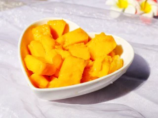 百变水果 芒果冰格,芒果洗净去皮,切开两边,用刀在芒果横竖各切几刀,翻起果皮切出芒果丁。