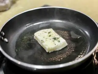 南法风味香煎银鳕鱼,取出腌制的鱼吸干油,撒上黑胡椒和盐 鱼皮朝下的先煎到7-8分熟。