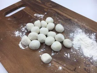 家乡风味饺子 三鲜馅饺子,拿出面团再把它们揉匀，取一块小块面团（其它的放回盆里保存），把它用双手搓成长条，再揪成小圆剂子。 