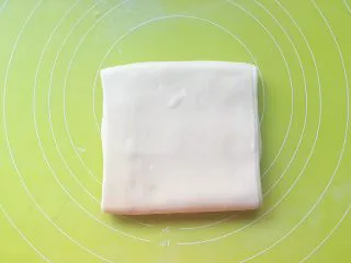意式红烩牛柳酥,将擀好的长条折成3折,这时候看一下面团的温度,如果面团温度还是冰凉的,可以继续操作,如果面团温度跟手温差不多,那就入冰箱冷冻10几分钟再做下一步