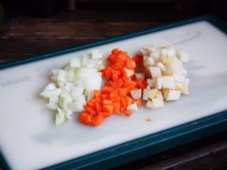 百变水果 新奥尔良风味雪梨烤鸡,将雪梨、洋葱、土豆、胡萝卜，放入烤盘里，撒入少许的盐、少许的黑胡椒碎、少许的孜然和辣椒粉、少许的橄榄油，将其拌匀备用。