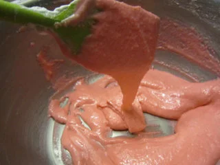 法式甜点马卡龙,直到蛋白糊的状态达到提起刮刀以后,蛋白糊呈带状往下飘落。裱花袋装一个圆形花嘴,把拌好的面糊装入裱花袋