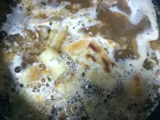 自制老北京小吃【卤煮】,如图将下入切好的羊肚肠子的卤汤锅煮开,下饼块儿,煮两分钟,加胡椒粉,调味