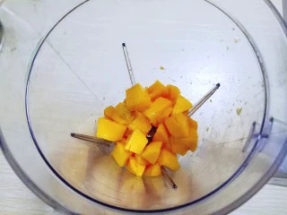 #冬喝暖饮夏吃冰#健康低卡-芒果酸奶昔,首先将切好的芒果肉加入料理机。(留两块果肉等一下做装饰)
