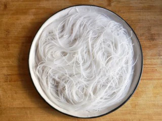 蒜蓉粉丝开背虾,将泡软的粉丝沥水后铺在盘底。