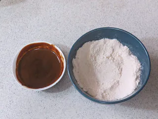 醇厚风味的咖啡百利甜费南雪,低粉、杏仁粉、泡打粉混合后过筛；速溶咖啡粉加热水泡开，然后加入百利甜酒混合备用