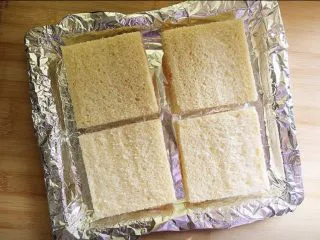 街头流行美食～【岩烧乳酪】,烤盘里铺锡纸，摆入四个吐司片。