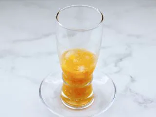 黄桃养乐多冰咖啡,把剩下的半个黄桃块碾成泥状，放入杯子底部。