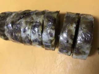 老北京清真小吃-糖卷果,将冷藏好的卷果取出,为保证好切块,不要立刻将保鲜膜揭下,要带着保鲜膜切成一公分厚的块。
