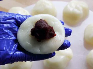 闽台风味茶点心豆沙糯米糍,10．取一份，按成圆饼。 放一小勺豆沙在中间。