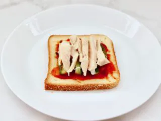 风味酸黄瓜鸡肉热压三明治,上面在铺上鸡肉条。