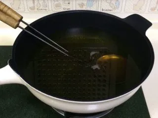 福建小吃—油饼,开大火,往锅内倒入食用油,把油饼勺一起放入锅内加热。