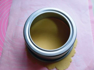 俄罗斯提拉米苏#异国美食#,准备两张油纸，下面垫一张，放上一小块面团，上面盖一张油纸，用擀面杖擀圆，之后用6寸模具压在饼皮上。