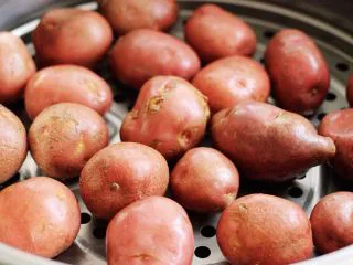 烧烤风味的香煎孜然小土豆,蒸笼锅里加入适量清水后，把清洗干净的红皮小土豆放入蒸笼锅中，盖上锅盖大火烧开后蒸20分钟后关火就可以了（也可以用水煮熟，但是我不喜欢水煮的土豆，口感差太多了，还是蒸出来的土豆口感更胜一筹哟）；