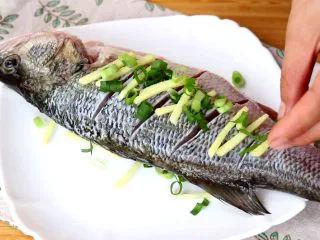 #年年有余#清蒸鲈鱼,放上鲈鱼,再在鲈鱼的表面撒上姜丝和葱末,放入冰箱冷藏腌制20min去腥