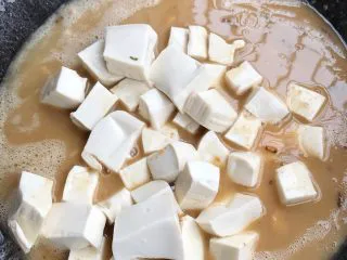 咸蛋豆腐(快手菜),大火煮开后,加入切好的豆腐。盖上锅盖煮至汁水减少。