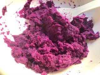 紫薯糯米丸子,倒入大一点的碗里，用勺子压碎。