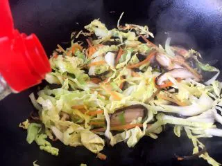 天津特色小吃 蔬菜烩饼,倒入1勺的酱油,翻炒均匀。