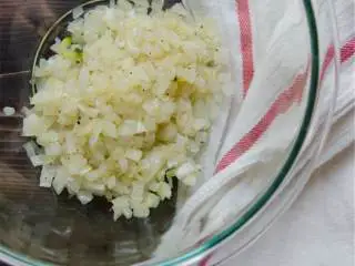 地中海风味火鸡肉丸,在平底锅里用中火加热一半橄榄油 ，加进洋葱和盐 ，加热直至洋葱变成半透明，然后倒进大碗里。