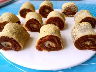 老北京小吃十三绝—驴打滚,切好的驴打滚在黄豆面里滚一圈，粘满黄豆面就行啦