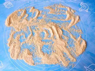 老北京小吃十三绝—驴打滚,案板上撒满炒熟的黄豆面