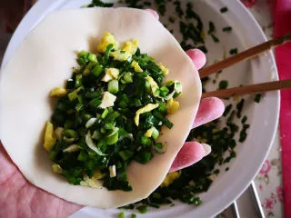 韭菜鸡蛋盒子,用擀面杖将面剂子擀圆，包上拌好的馅，稍按扁， 