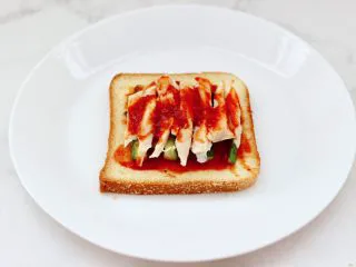 风味酸黄瓜鸡肉热压三明治,再抹上剩下的一勺披萨酱。