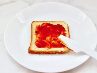 风味酸黄瓜鸡肉热压三明治,取一片吐司，上面先均匀抹上一勺披萨酱。