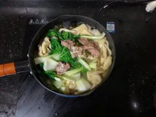 河南小吃-羊肉烩面,19、放入青菜,烹入少许的盐调味。