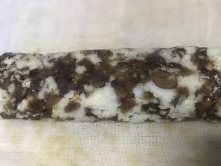 老北京清真小吃-糖卷果,反复折叠卷几次,就可以将卷果弄紧,成圆柱体。这一步一定要卷紧,否则到后面切块的时候会散掉。折叠卷的时候两侧的会挤出去,这时候可以往中间整理一下。