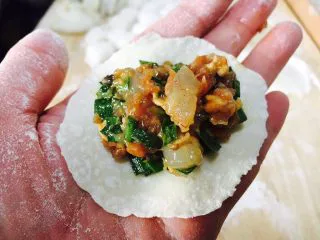 家乡风味饺子 三鲜馅饺子,往饺子皮上放适量的饺子馅。 