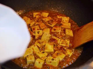 正宗地道的麻婆豆腐,煮到还剩少量汤汁时，倒入水淀粉。用铲子轻推。