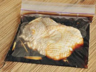 照烧风味鸡腿饭,鸡腿肉拍松后用刀尖扎几下加快入味，然后与姜丝/姜泥、腌汁一同放入密实袋中，放冰箱冷藏腌制至少30分钟。（可以的话最好提前一晚开始腌制鸡肉，这样第二天做起来更快） 