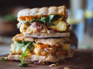 全素三明治配西班牙风味酱汁,用锯齿刀把三明治切成两半，配上剩余的凉拌卷心菜一起吃。