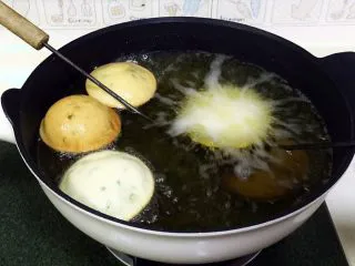 福建小吃—油饼,然后把油饼勺放入锅底,可看见大量气泡冒出,十几秒后油饼就慢慢鼓起来了,浮到油锅表面,待油饼一面炸至金黄色后,翻一面继续。