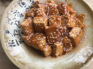 做道小朋友也爱吃的酸甜豆腐,豆腐倒入盘中，洒上白芝麻装饰。