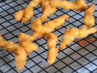 街头小吃自己做---香酥无骨鸡柳,放到晾网上沥去多余油份。