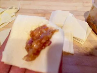 乡味~重庆小吃红油抄手,手拿一张面皮放入肉馅。