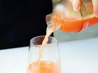 夏日红柚季！比基尼少女的鸡尾酒,在玻璃杯中加适量的冰块，将鸡尾酒倒入杯中