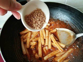 韩式辣炒年糕，炙手可热的小吃,年糕条炒软，最后倒入芝麻。