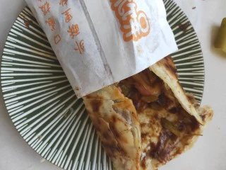 街头手抓饼的吃法----懒人必备早餐,卷起来放入纸袋中,懒人早餐就做好了。