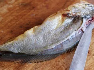 清蒸剁椒黄花鱼,把黄花鱼放在菜板上、用刀先在黄花鱼的头部开始片刀到黄花鱼的鱼尾处、切记不要把黄花鱼的肚子切开呀