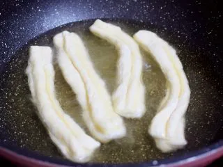自制健康油条,锅中倒入适量的食用油，待油温7-8成热时，放入油条生胚