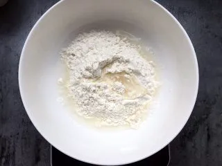 四川乐山名小吃—粉蒸肉卡饼,将面粉加入温水搅匀揉成面团。