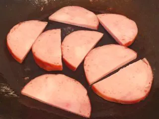 手抓饼开心早餐,锅中倒入少许底油摆入火腿片