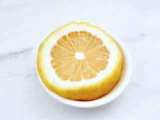 橘子蔓越莓蜂蜜冰饮,把柠檬洗净后用刀切成片。